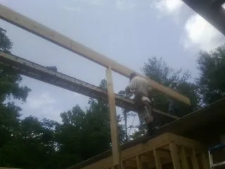 Carpenter setting a ridge beam over a new addition frame — Ice Dam Removal by Roofing Brothers in Lemon Springs