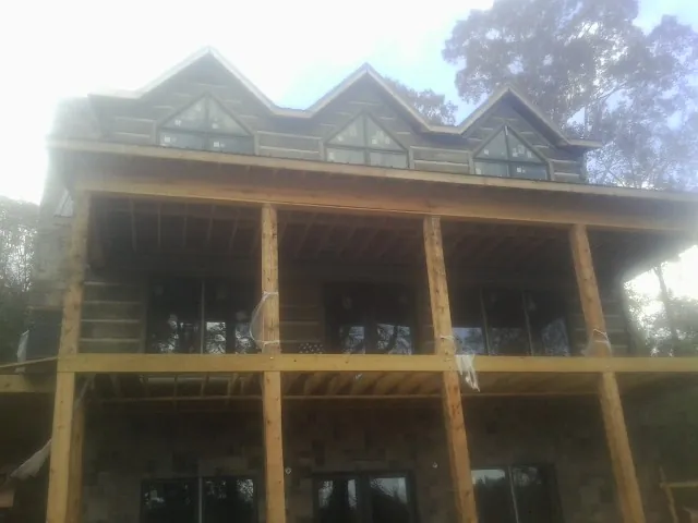 Dormers and porch framing on a large log home under construction — Roof Coating work by our crew in Lemon Springs