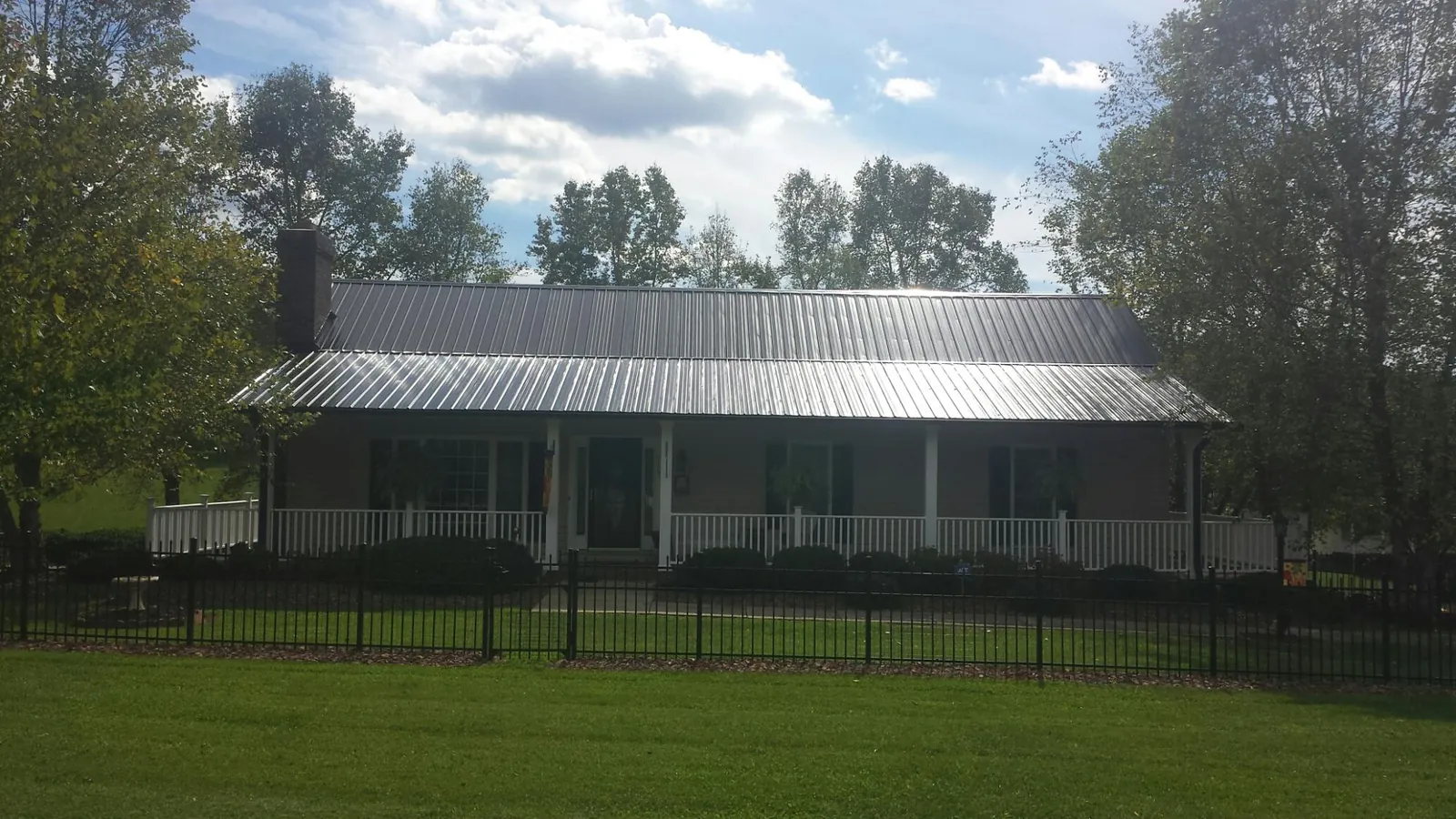 Gray metal roof on a brick ranch with a full width front porch — Gutter Guard Installation work by our crew in Lemon Springs