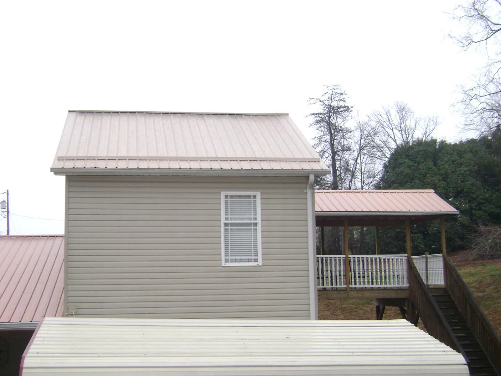 Tan metal roofs on a two story addition and attached porch in Lemon Springs