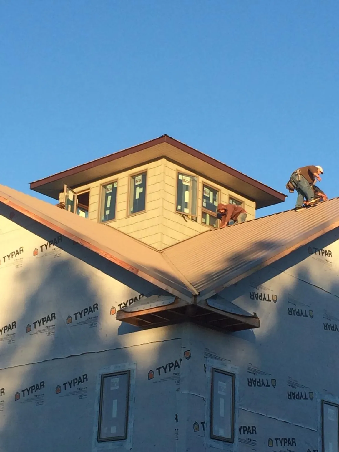 Roofers working around a rooftop cupola on a new metal roof at sunset — Roof Waterproofing in Lemon Springs by Roofing Brothers